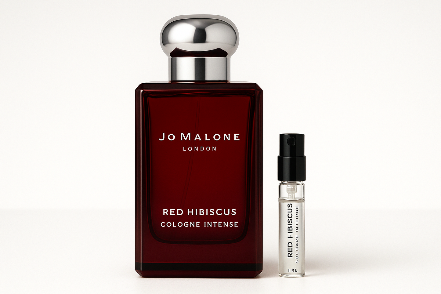 Próbka wody kolońskiej Jo Malone Red Hibiscus Intense 1 ml obok 100 ml butelki perfum Jo Malone Red Hibiscus Intense z białym napisem na ciemnoczerwonej butelce